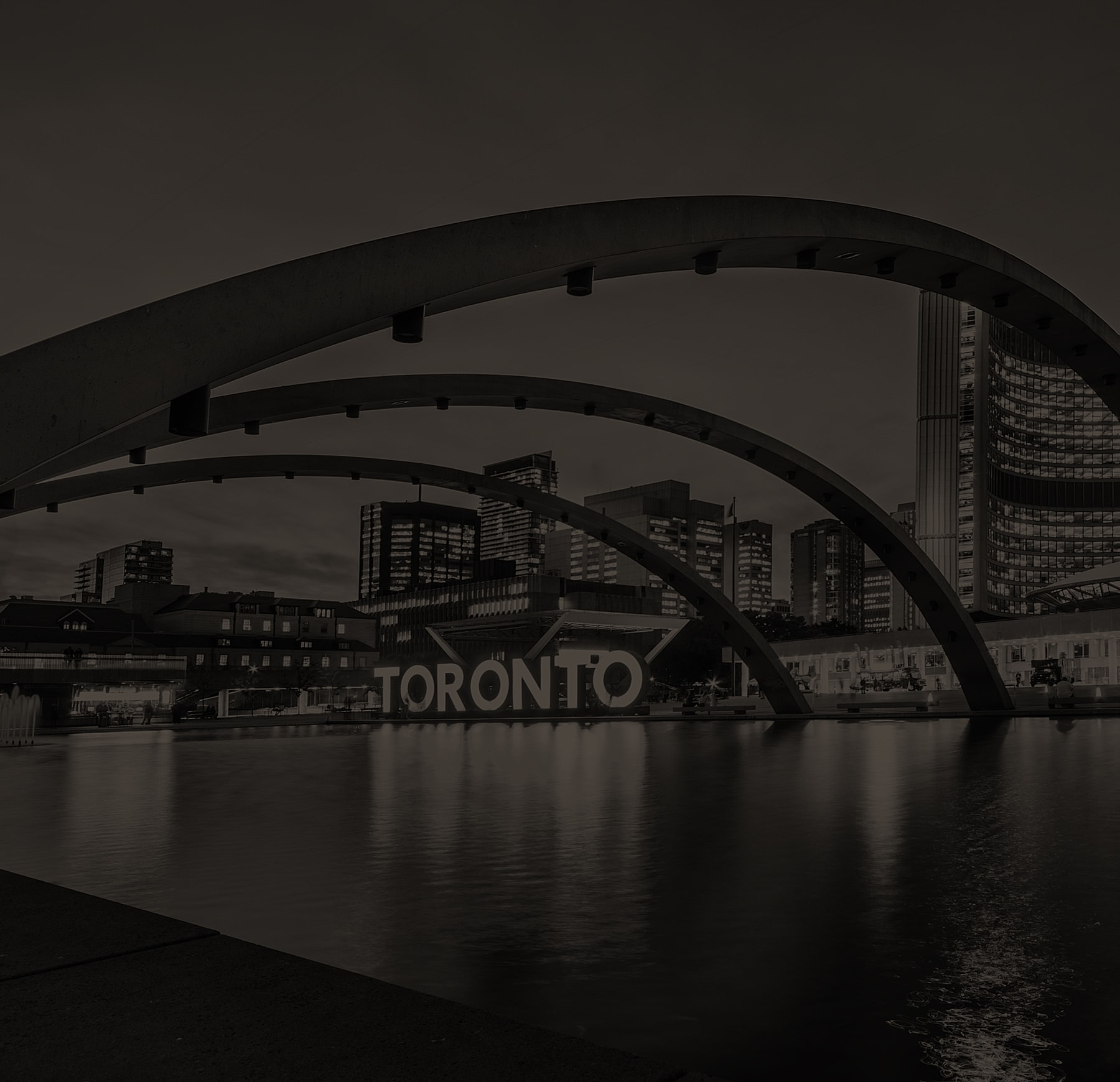 Toronto skyline with arches and water reflection.