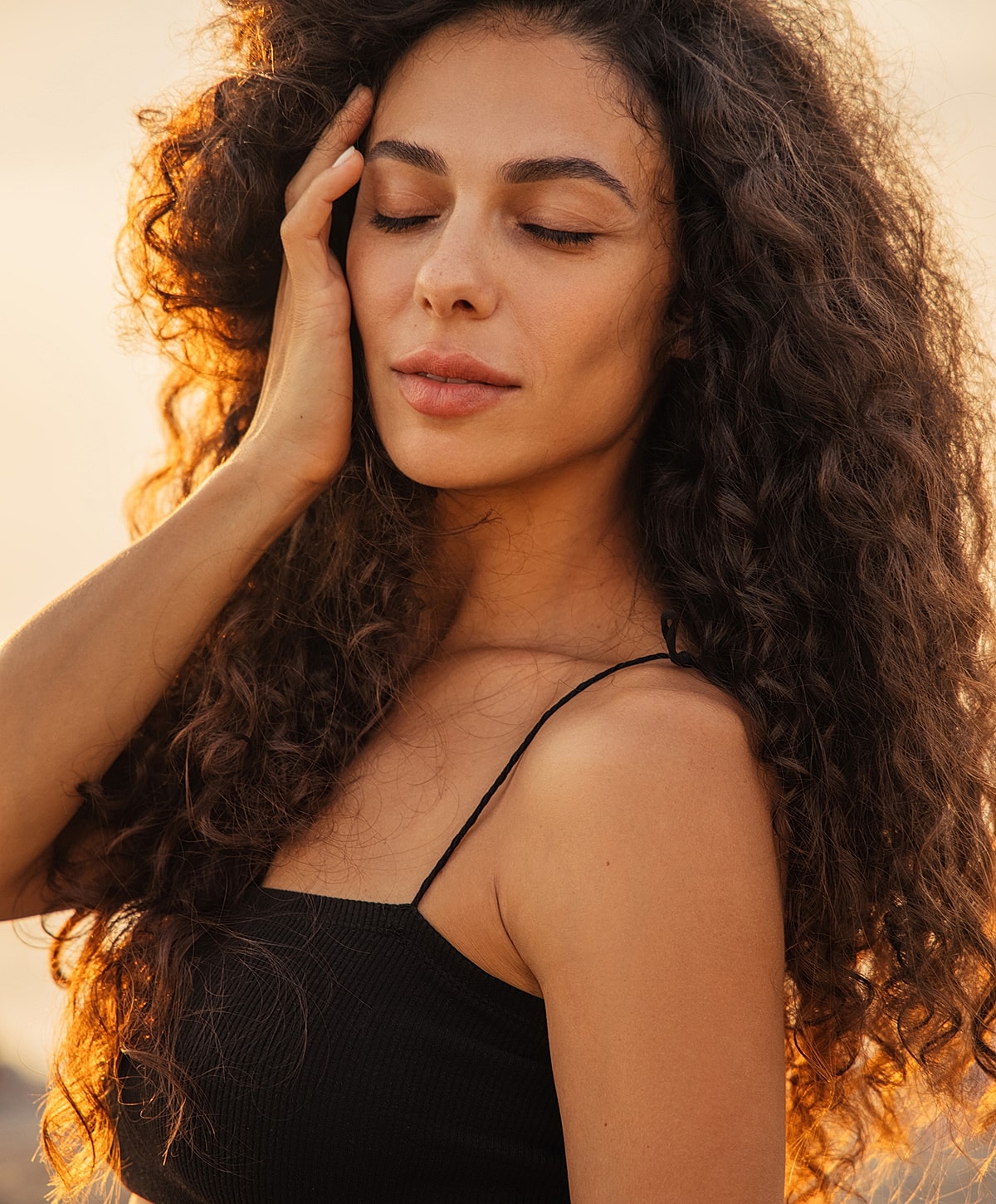 Woman with curly hair enjoying sunset.