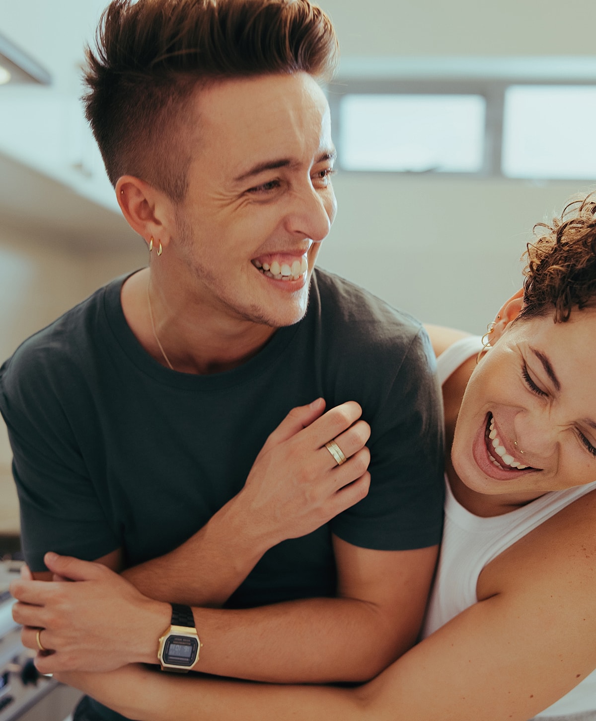 Two friends joyfully embracing in a kitchen.