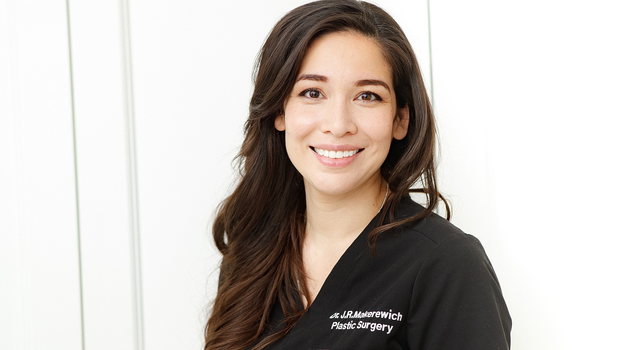 Smiling professional in black medical attire.