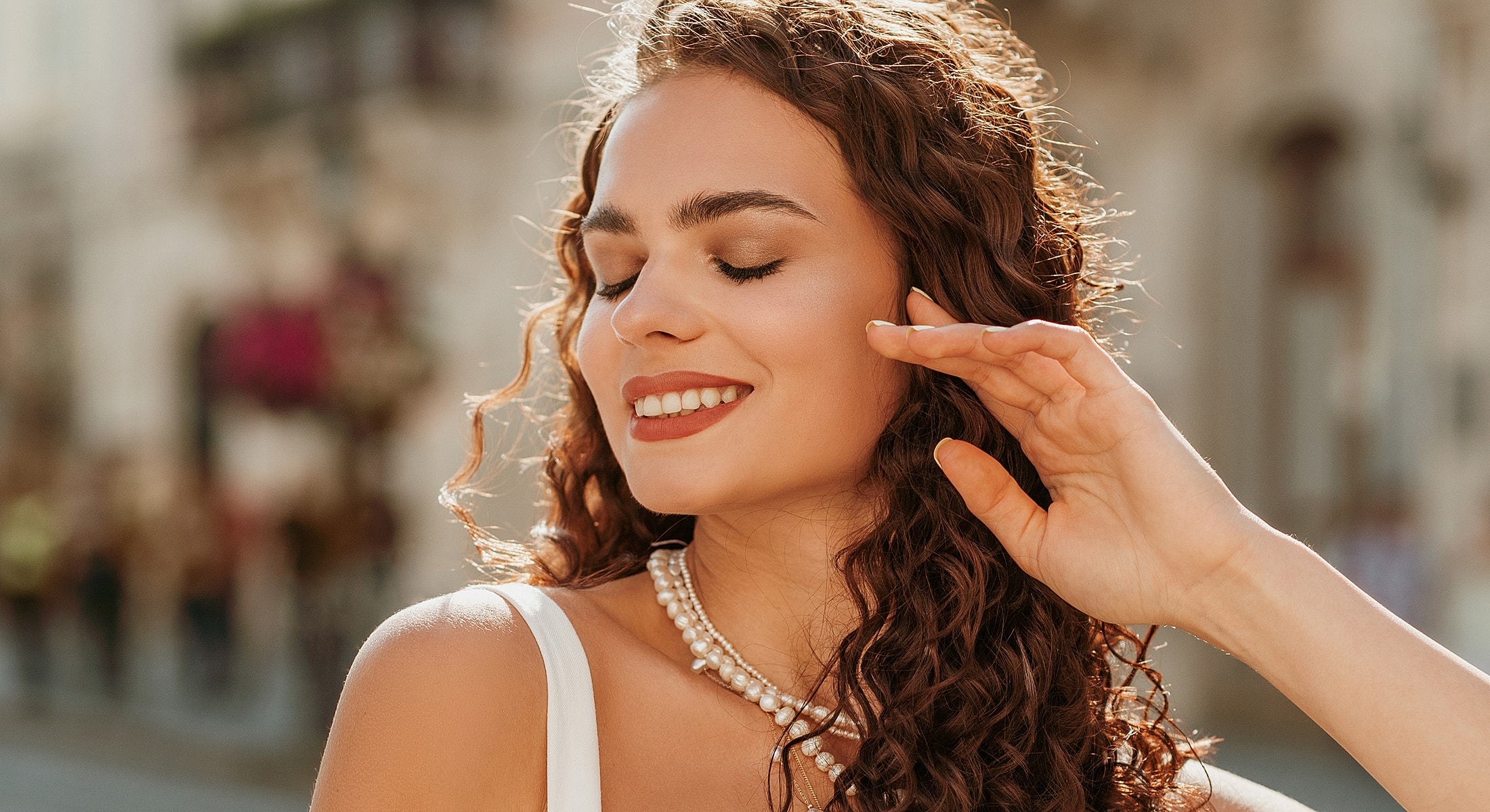 Woman with curly hair smiling outdoors.