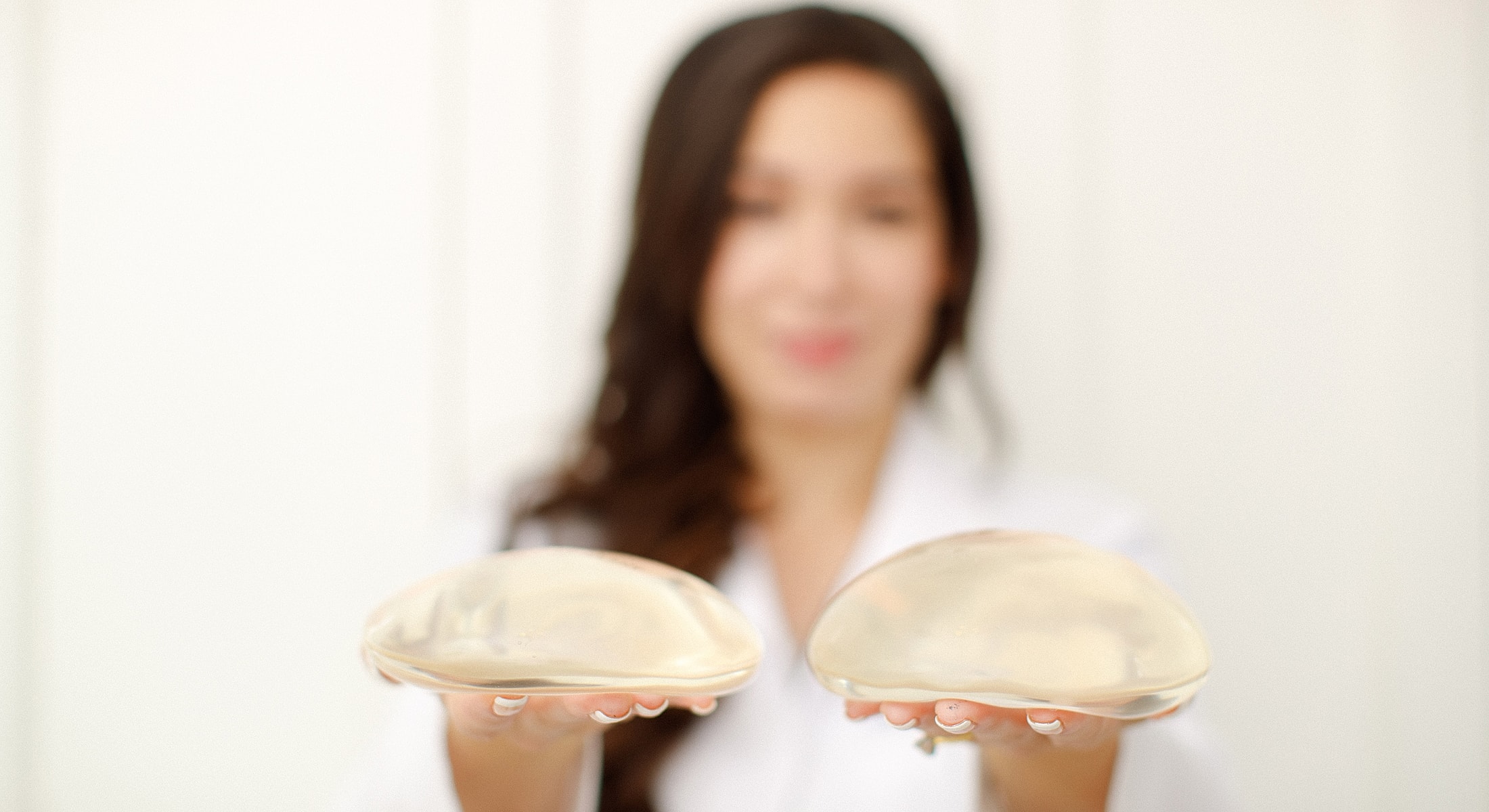 Woman holding silicone breast implants in hands.